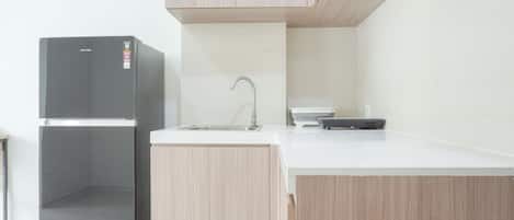 A kitchen with a black refrigerator, a sink, and wooden cabinets.