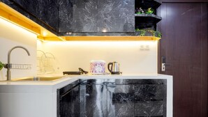 A modern kitchen with a white countertop, black marble cabinets, a stainless steel sink, and a built-in oven. - Nice And Comfort 2Br At Daan Mogot City Apartment (Jakarta)