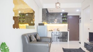 A modern living room with a leather sofa, a black rug, and a kitchen area with marble countertops and a refrigerator. - Nice And Comfort 2Br At Daan Mogot City Apartment (Jakarta)
