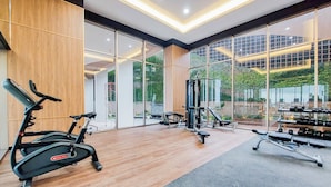A modern gym with cardio equipment, weight machines, and dumbbells. - Cozy Living Studio At Transpark Bintaro Apartment (South Tangerang)