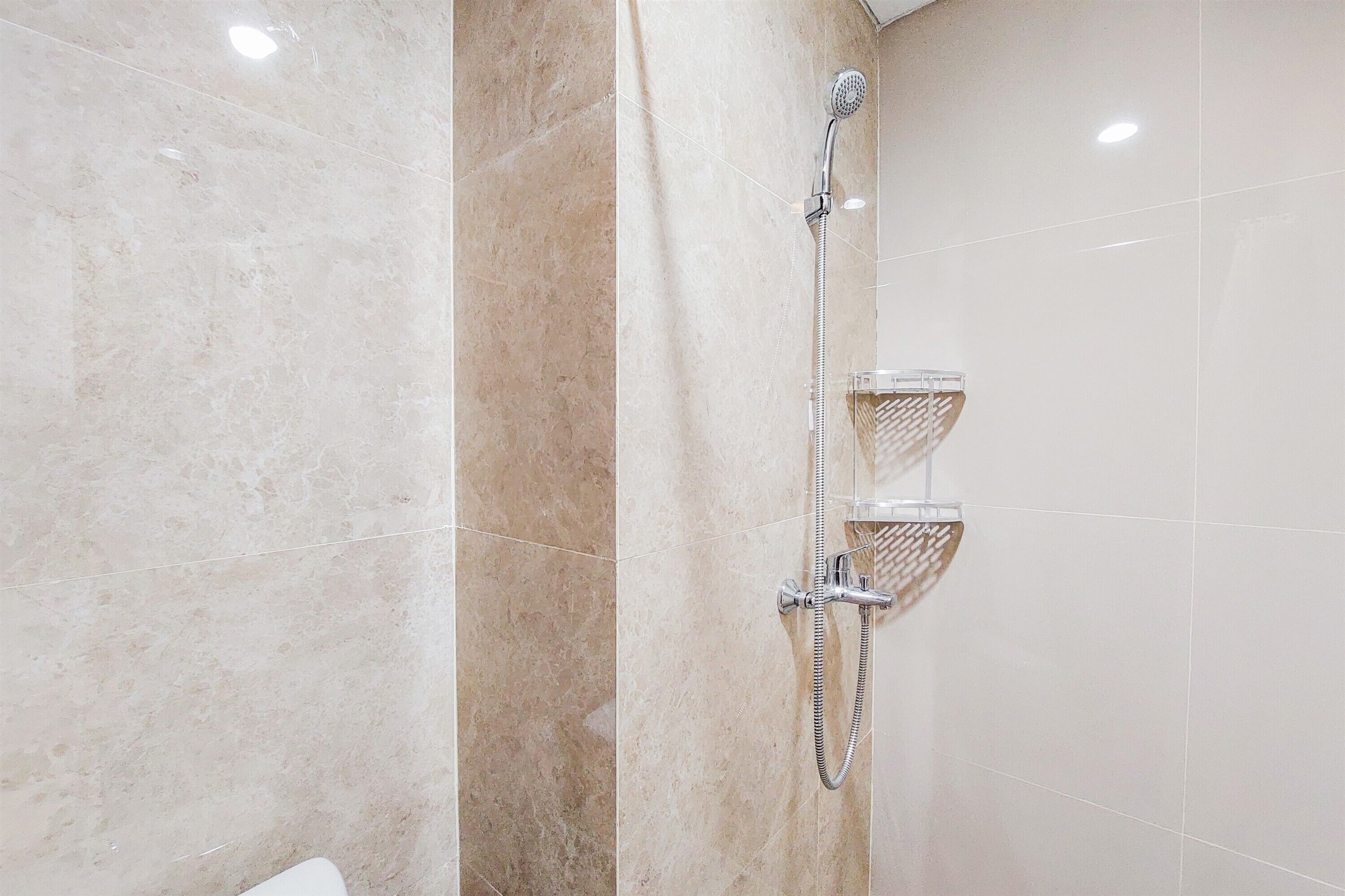 A bathroom with a shower, a towel rack, and a tiled wall.
