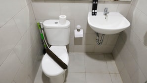 A bathroom with a toilet, a sink, and a toilet paper holder. - Aesthetic 2Br Connected To Mall At Supermall Mansion Apartment (Surabaya)