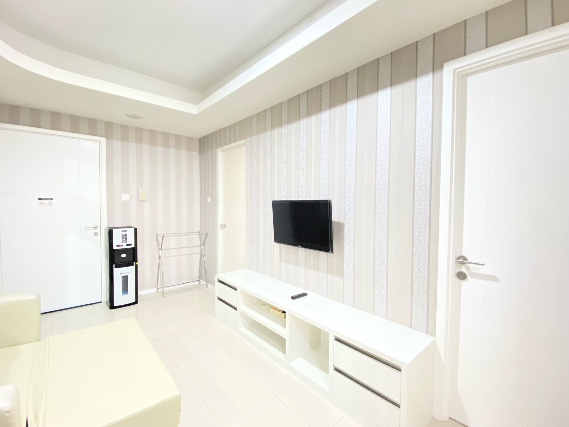 Een moderne hotelkamer met een groot bed, een aan de muur bevestigde televisie, een zitje en een deur.