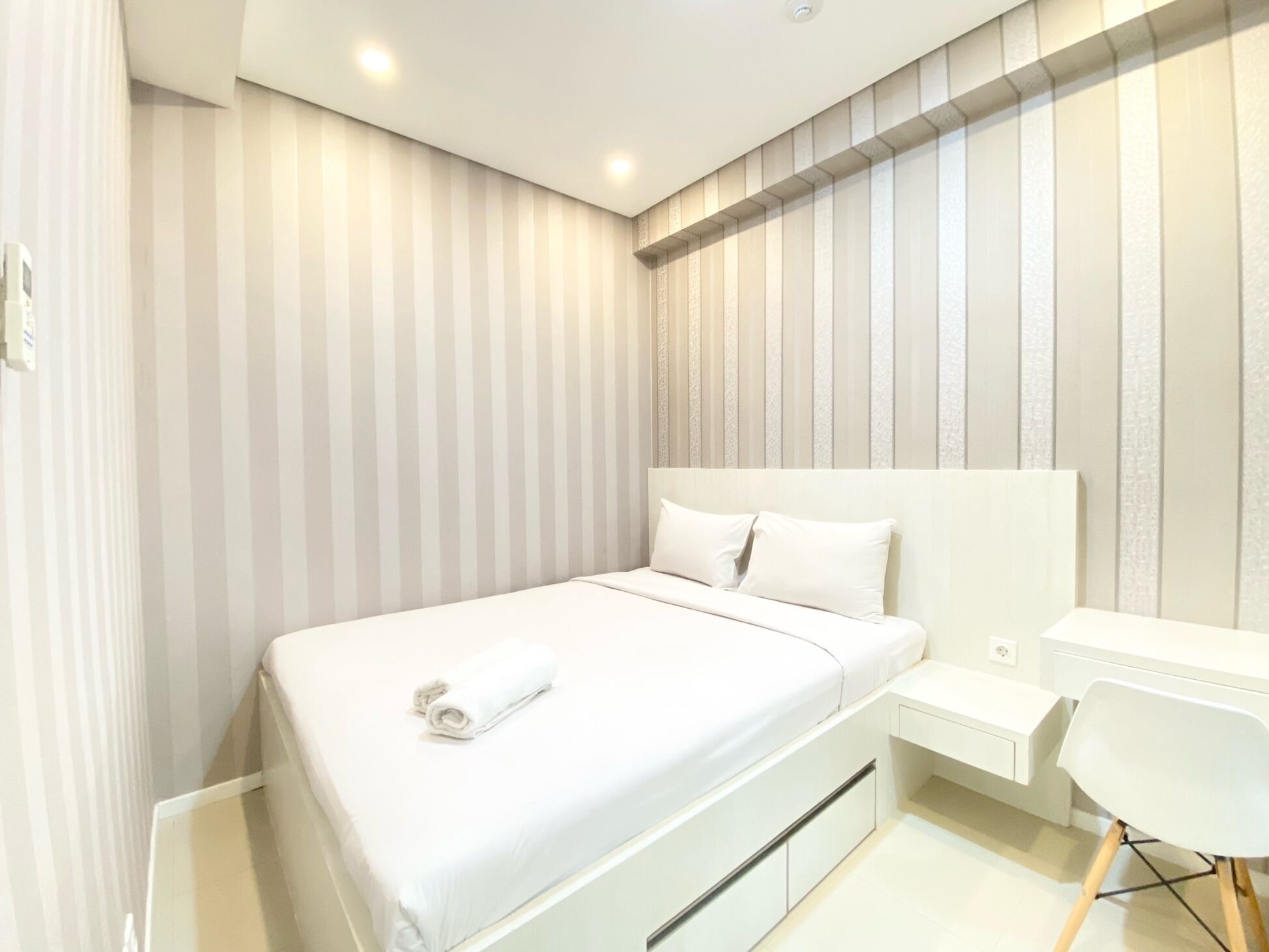 Un dormitorio moderno con una cama grande, una mesita de noche y una silla.
