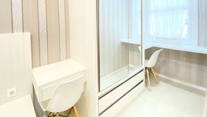 A modern, minimalist room with a white desk, chair, and a large window with sheer curtains.