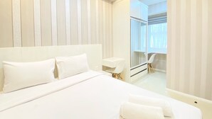 A hotel room with a large bed, a bedside table, a mirror, and a view of a bathroom.
