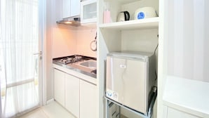 A compact kitchen with white cabinets, a gas stove, a microwave, and a refrigerator.