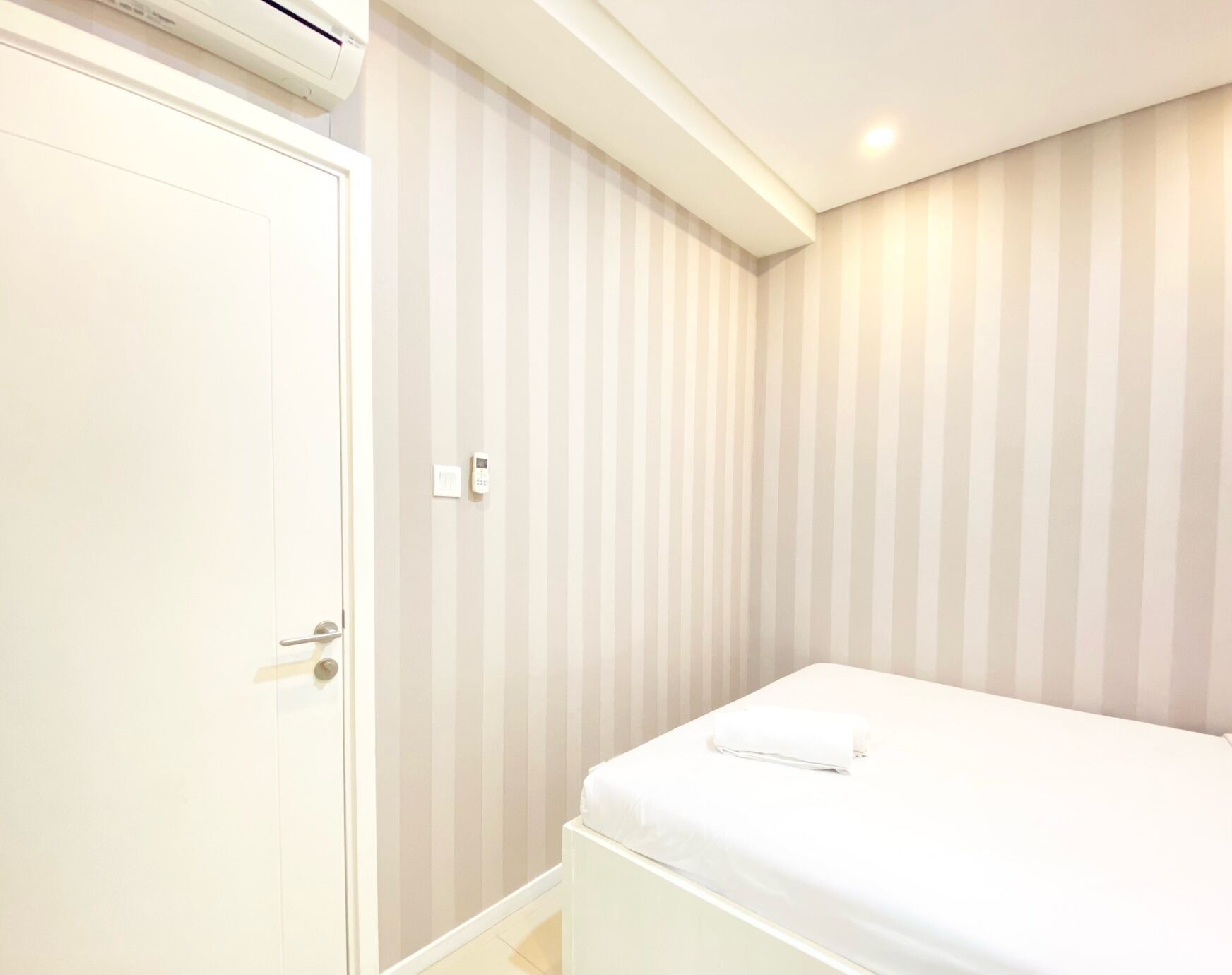 Une chambre à coucher avec un lit, une porte et un mur orné de rayures verticales.