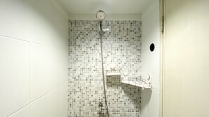 A shower with a polka dot tile pattern, a handheld showerhead, and a wall-mounted faucet. - Comfortable Studio Apartment For 1 Pax Grand Sentraland Karawang (Karawang)