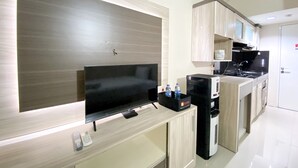 A modern kitchen with a flat-screen TV, a coffee machine, and a microwave. - Comfortable Studio Apartment For 1 Pax Grand Sentraland Karawang (Karawang)