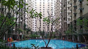 A swimming pool surrounded by greenery and tall residential buildings. - Nice 2Br Apartment At Gateway Ahmad Yani Cicadas (Bandung)