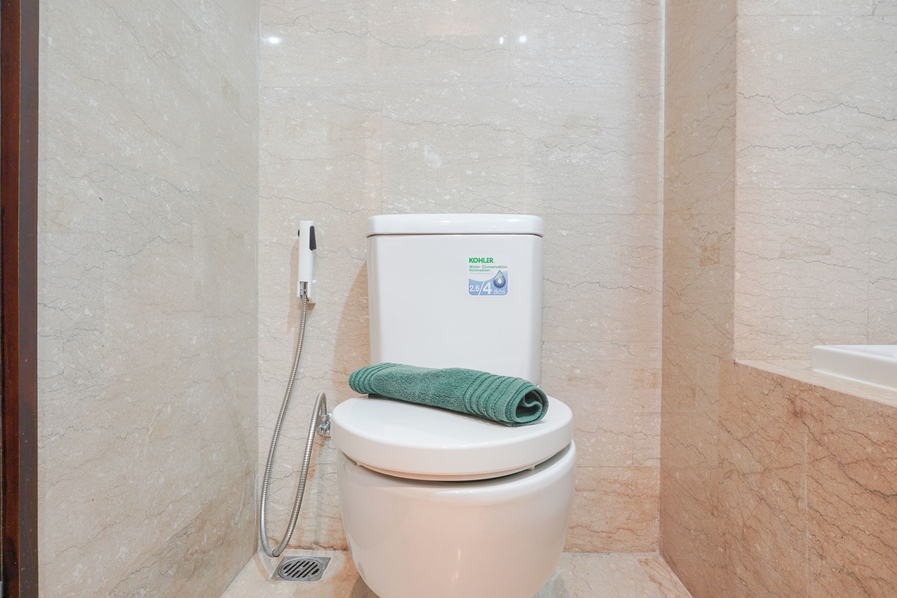 A bathroom with a toilet, a towel, and a shower.