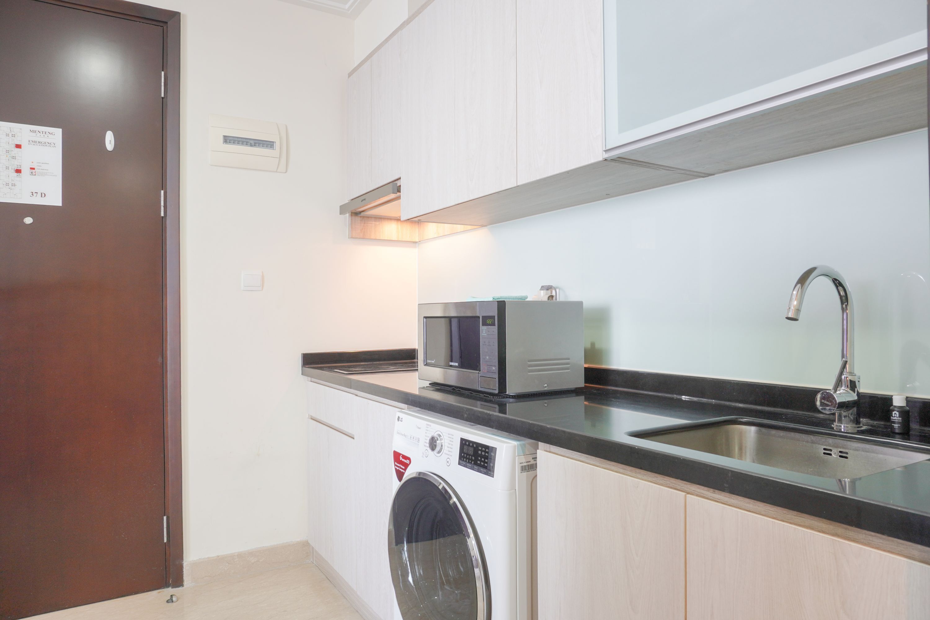 A compact kitchen with a washing machine, a microwave, and a sink.