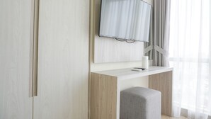 Ein modernes Zimmer mit Flachbildfernseher an einer Holzwand, einem kleinen Tisch mit einer Tasse und einer grauen Bank.