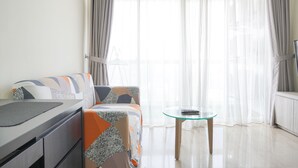 Ein modernes Wohnzimmer mit einer Couch, einem Glastisch und einem Fernseher.