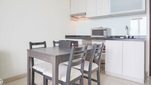 A modern kitchen with a dining area, featuring a central island, white cabinetry, and a built-in microwave. - Nice And Elegant 2Br At 26Th Floor Menteng Park Apartment (Jakarta)