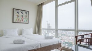 A hotel room with two beds, a large window with a city view, and a table with a chair. - Nice And Elegant 2Br At 26Th Floor Menteng Park Apartment (Jakarta)