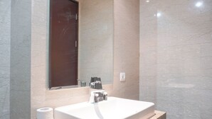 A bathroom with a white sink, a mirror, and a marble wall. - Nice And Elegant 2Br At 26Th Floor Menteng Park Apartment (Jakarta)