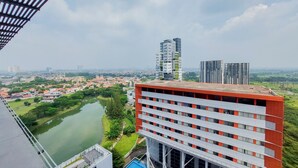 A high-rise building with multiple floors, a river in the foreground, and a cityscape in the background. - Elegant And Spacious 2Br At Paddington Heights Apartment (Tangerang)