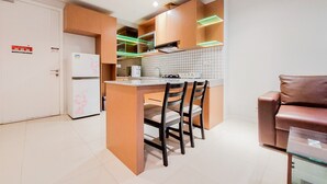 A compact kitchen with a central island, wooden cabinets, and a refrigerator. - Elegant And Spacious 2Br At Paddington Heights Apartment (Tangerang)