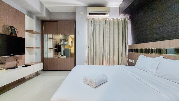 Een hotelkamer met een bed, een televisie, een spiegel en een raam met gordijnen.