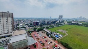 Stadsgezicht met een grote parkeerplaats, moderne gebouwen en een groen veld.