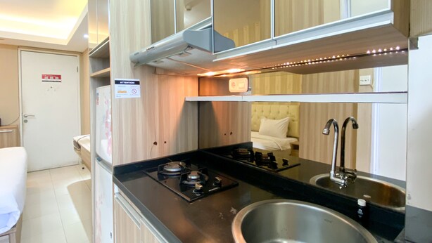 A compact kitchen with a gas stove, stainless steel sink, and a small countertop. - Cozy And Comfy Studio At Bassura City Apartment (Jakarta)