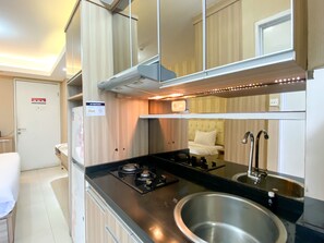 A compact kitchen with a gas stove, stainless steel sink, and a small countertop.
