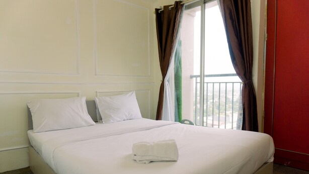 A hotel room with a large bed, white linens, and a neatly folded towel.