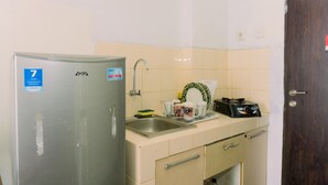 A compact kitchen with a stainless steel refrigerator, a sink, and a stove.