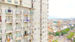 Ein Hochhaus mit mehreren Balkonen, Klimaanlagen und Blick auf eine Stadtlandschaft.