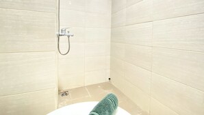 Ein kleines Badezimmer mit Fliesen, einer Dusche und einem Waschbecken.