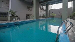 Ein Innenpool mit klarem, blauem Wasser, umgeben von gefliesten Wänden und Säulen, ausgestattet mit Metallleiter.