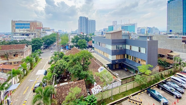 A cityscape with modern buildings, a parking lot, and a street with cars. - Spacious 2Br Apartment At Grand Asia Afrika (Bandung)