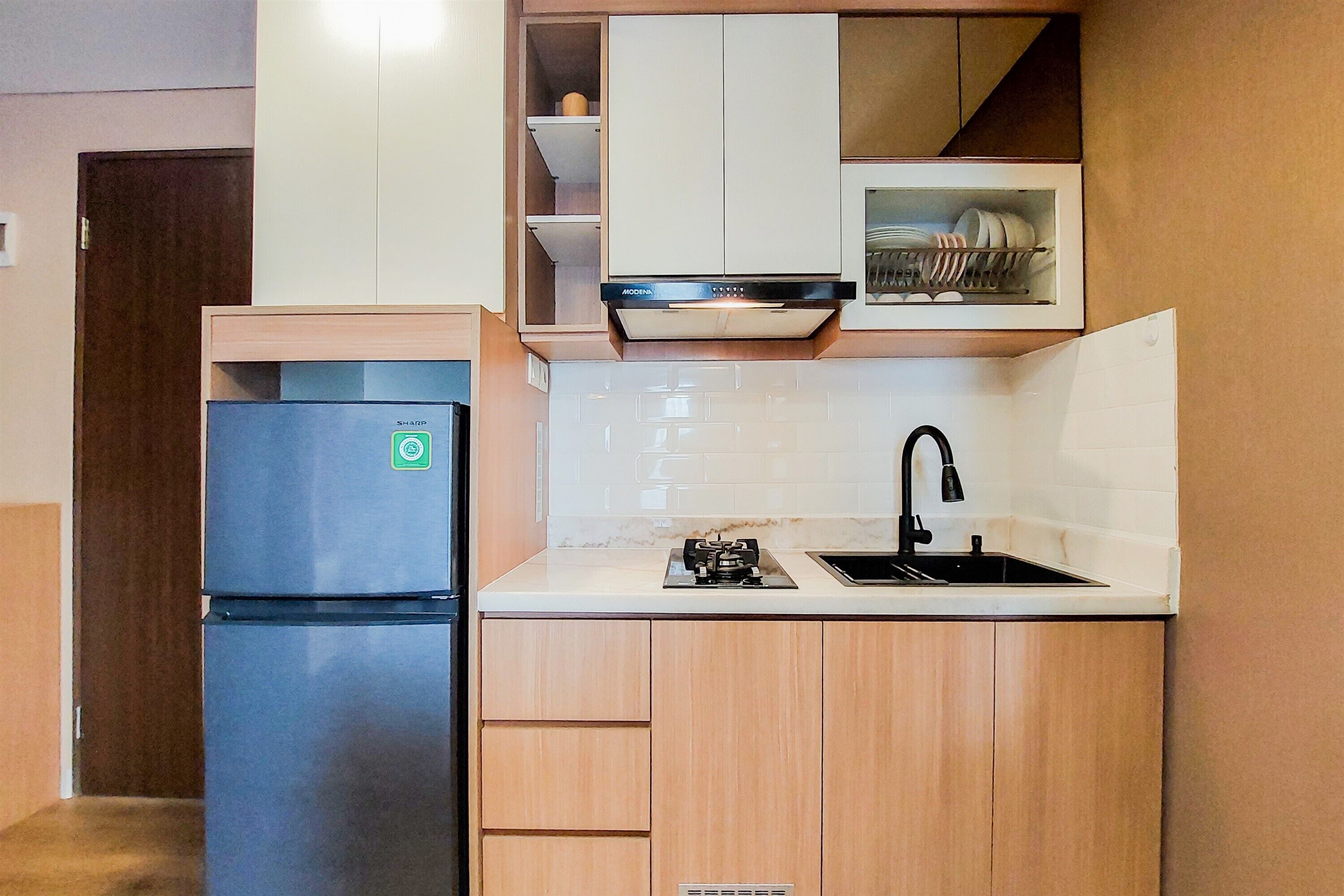 Una cocina compacta con refrigerador empotrado, un lavamanos y armarios de madera.