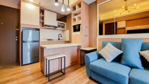 A compact kitchen with a built-in fridge, microwave, and a small dining area. - Best Choice And Comfy 2Br At Transpark Bintaro Apartment (South Tangerang)