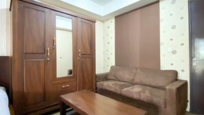 Una habitación con un sofá marrón, una mesa de madera y un armario con puertas espejadas.