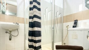 Un baño con ducha, inodoro, lavabo y puerta de cristal para la ducha.