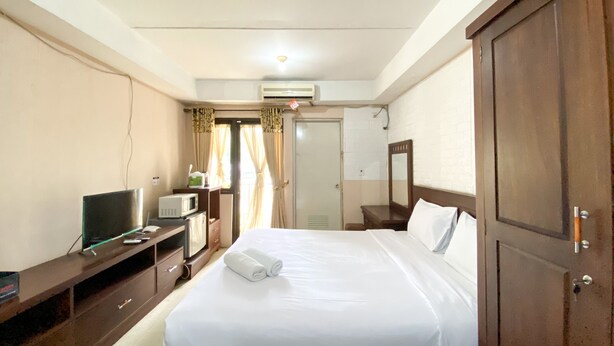 Una habitación de hotel con una cama, televisión, microondas y armario.