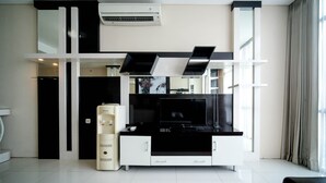 A modern living room with a flat-screen TV, a water dispenser, and a built-in air conditioning unit.