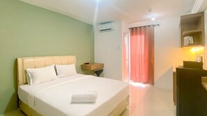 A hotel room with a bed, a nightstand, a desk, and a window with curtains.