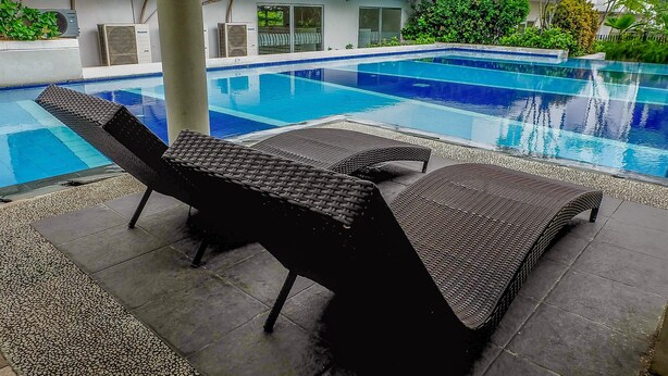 A swimming pool with lounge chairs and a tiled deck.