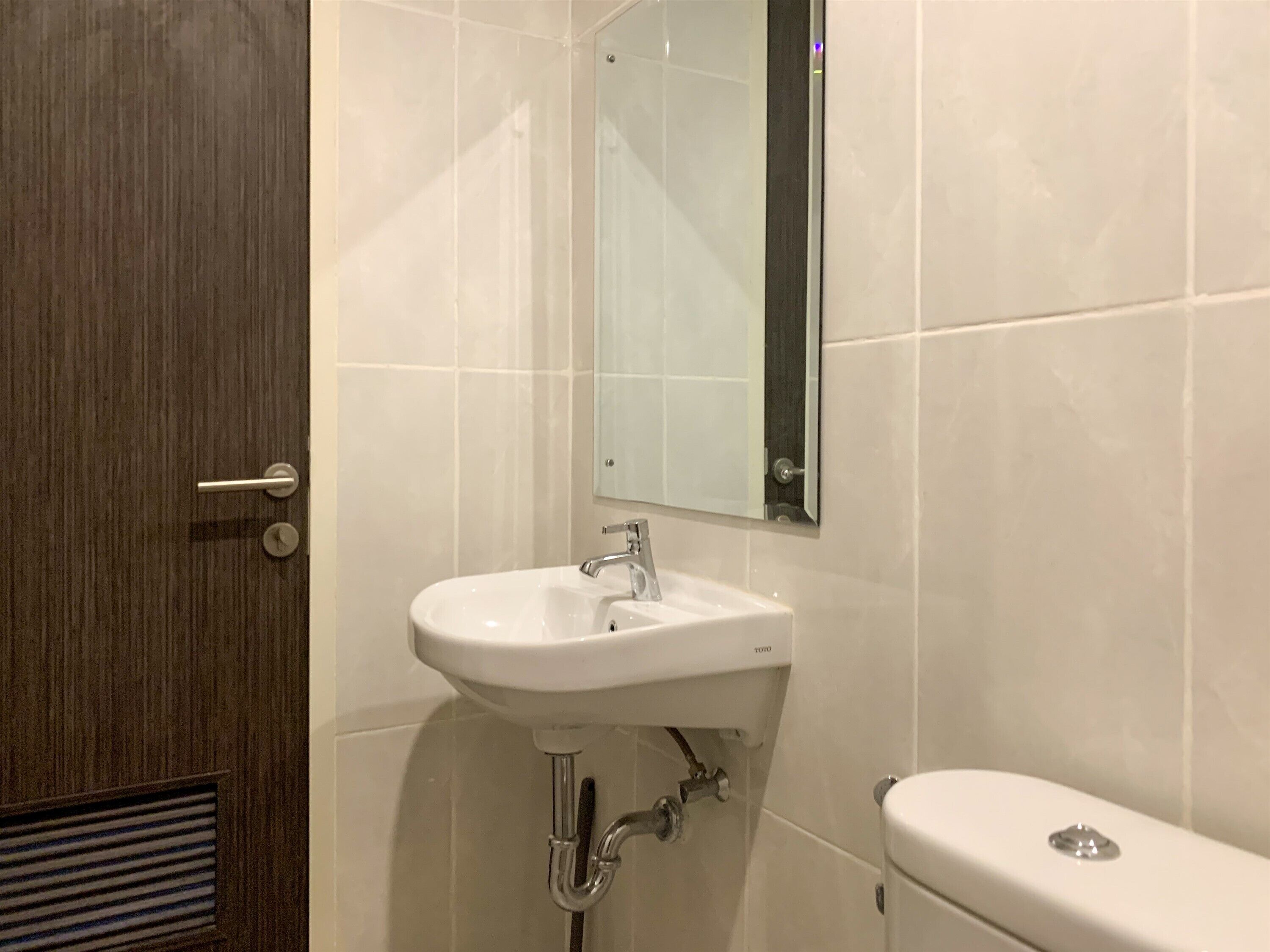 Une salle de bain avec un lavabo blanc, un miroir et des toilettes.