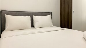 A neatly made bed with a grey headboard and two white pillows. - Homey And Simply 2Br At Serpong Garden Apartment (Cisauk)
