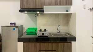 A compact kitchen with a stove, sink, and cabinets. - Homey And Simply 2Br At Serpong Garden Apartment (Cisauk)