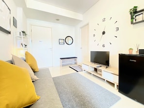 Ein modernes Wohnzimmer mit einer Couch, einem Fernseher und einer großen Wanduhr.