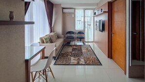 Un salon moderne avec un canapé, des fauteuils, une table basse en verre et un tapis à motifs.