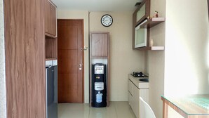 Une cuisine compacte équipée d’une machine à café, d’une horloge et d’un petit coin repas.