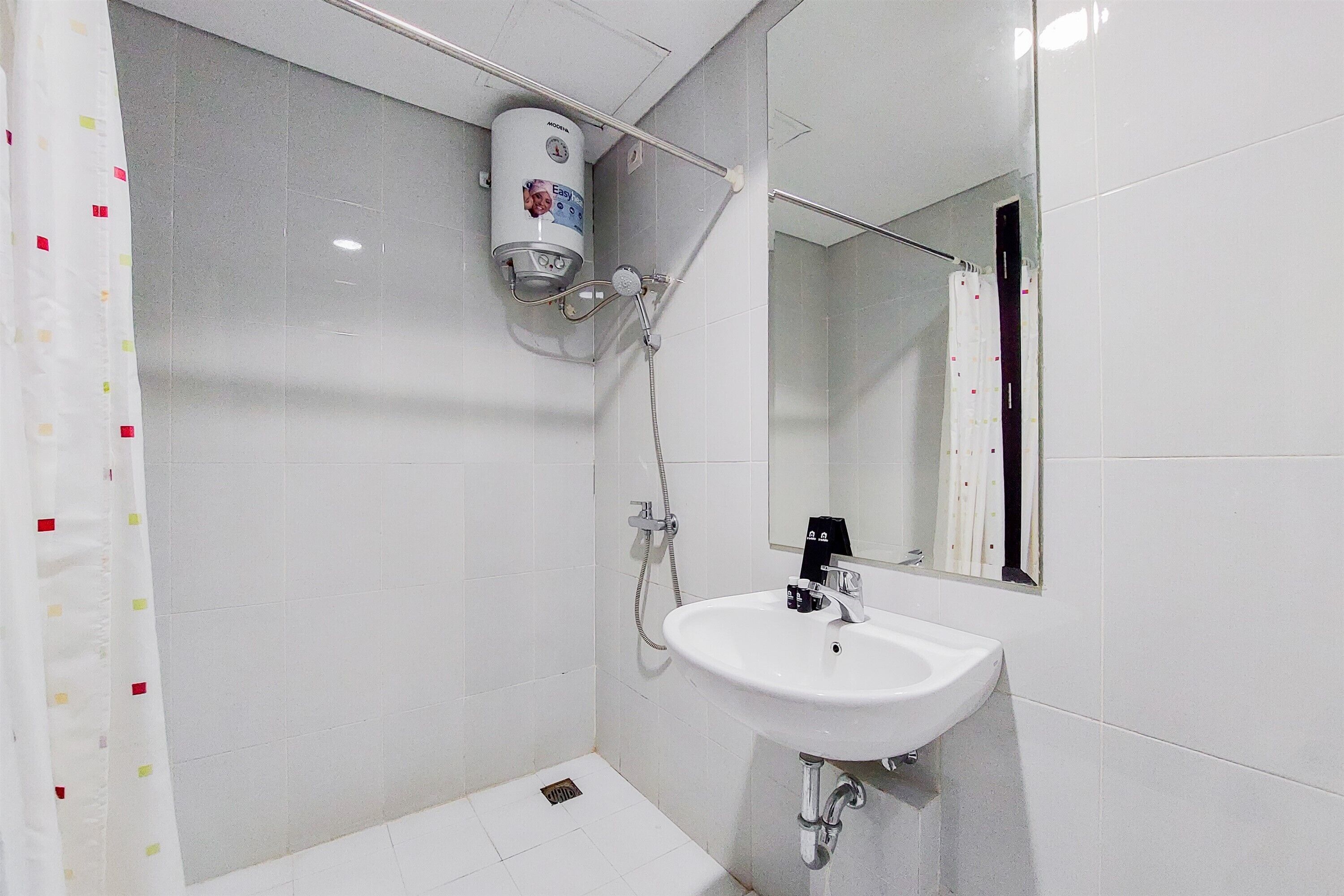 A bathroom with a white sink, a handheld showerhead, and a wall-mounted water heater.