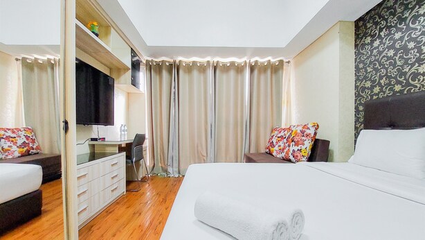 Camera d'albergo con un ampio letto, una scrivania, una sedia e una televisione.